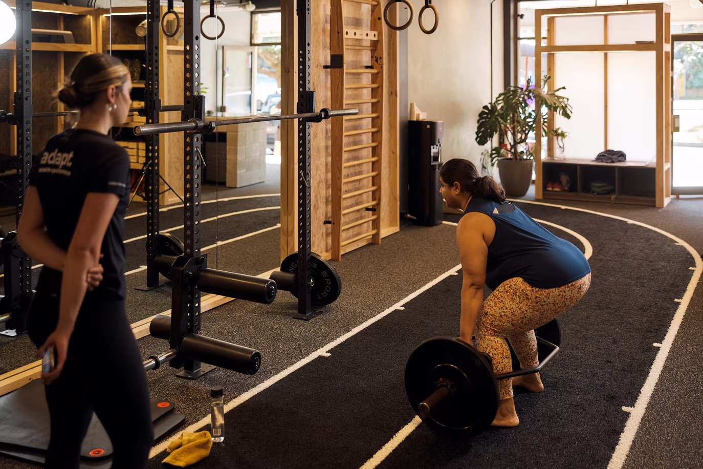 Coach cueing a squat during a supervised session at Adapt, North Sydney
